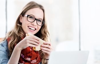 Businesswoman working while eating sandwich in her desk in office